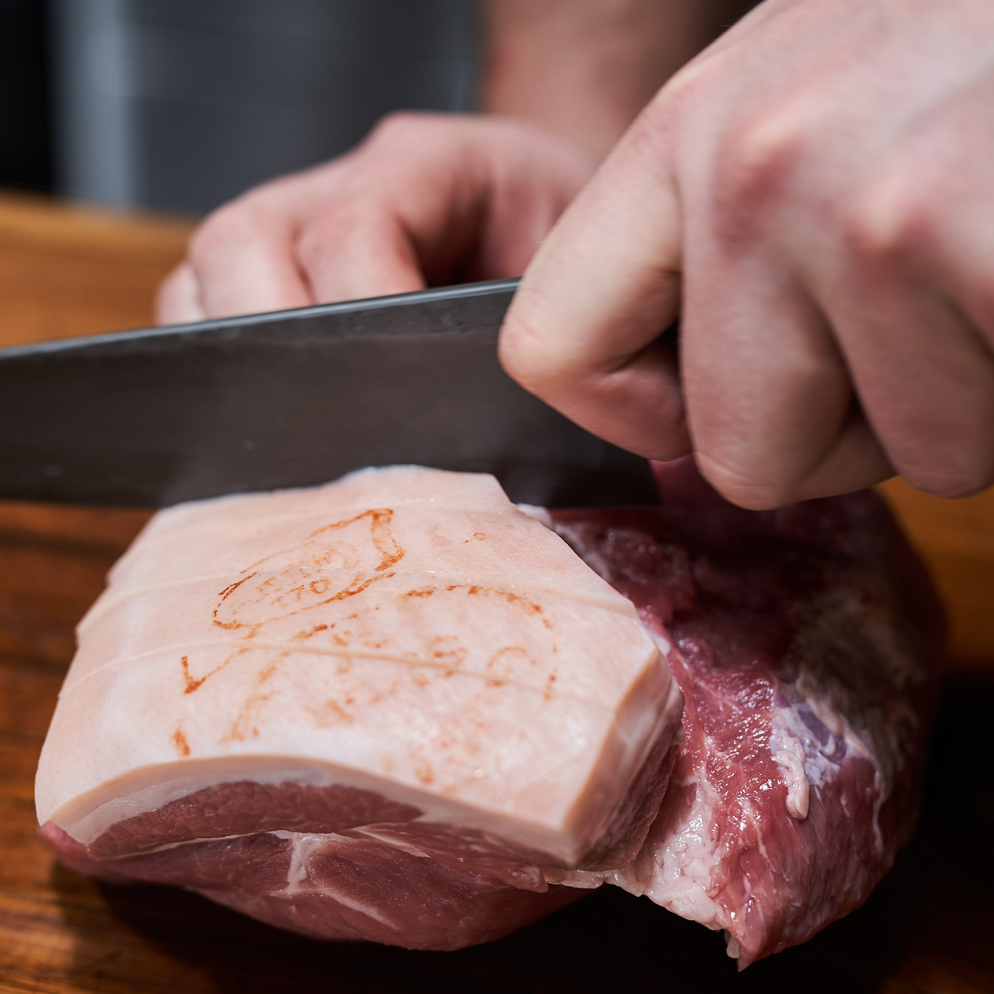 Schopf mit Schwarte vom Strohschwein Schwarte vom Schopf wird mit Messer eingeschnitten