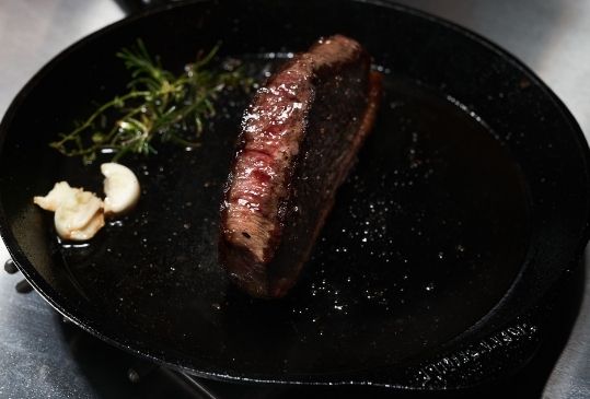 Steak wird in Gusseisenpfanne zubereitet.