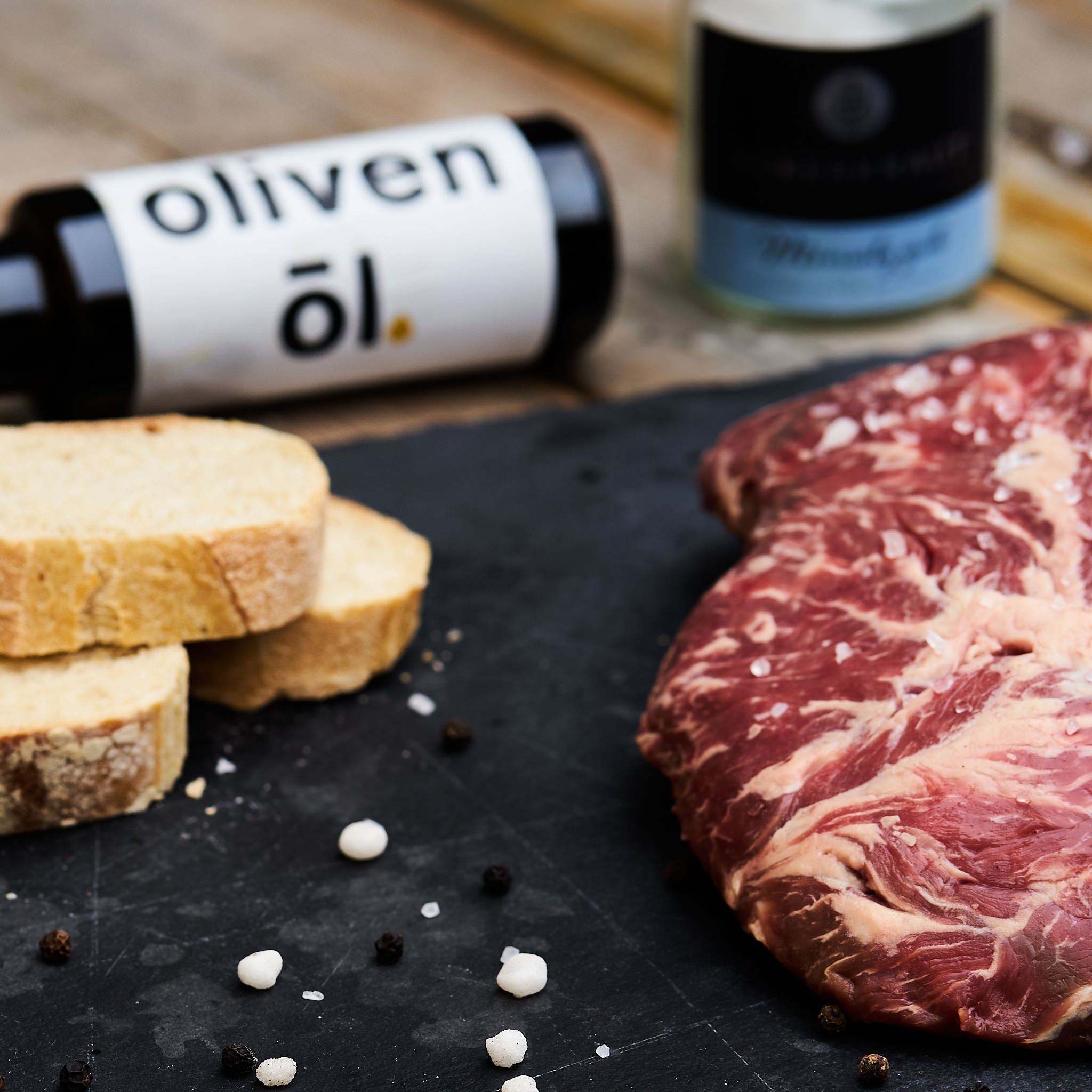 Fledermaus Steak vom Rind - Spider Steak Fledermaus Steak auf schwarzer Steinplatte mit frischem Weissbrot und einer Flasche Fitmeat Oel