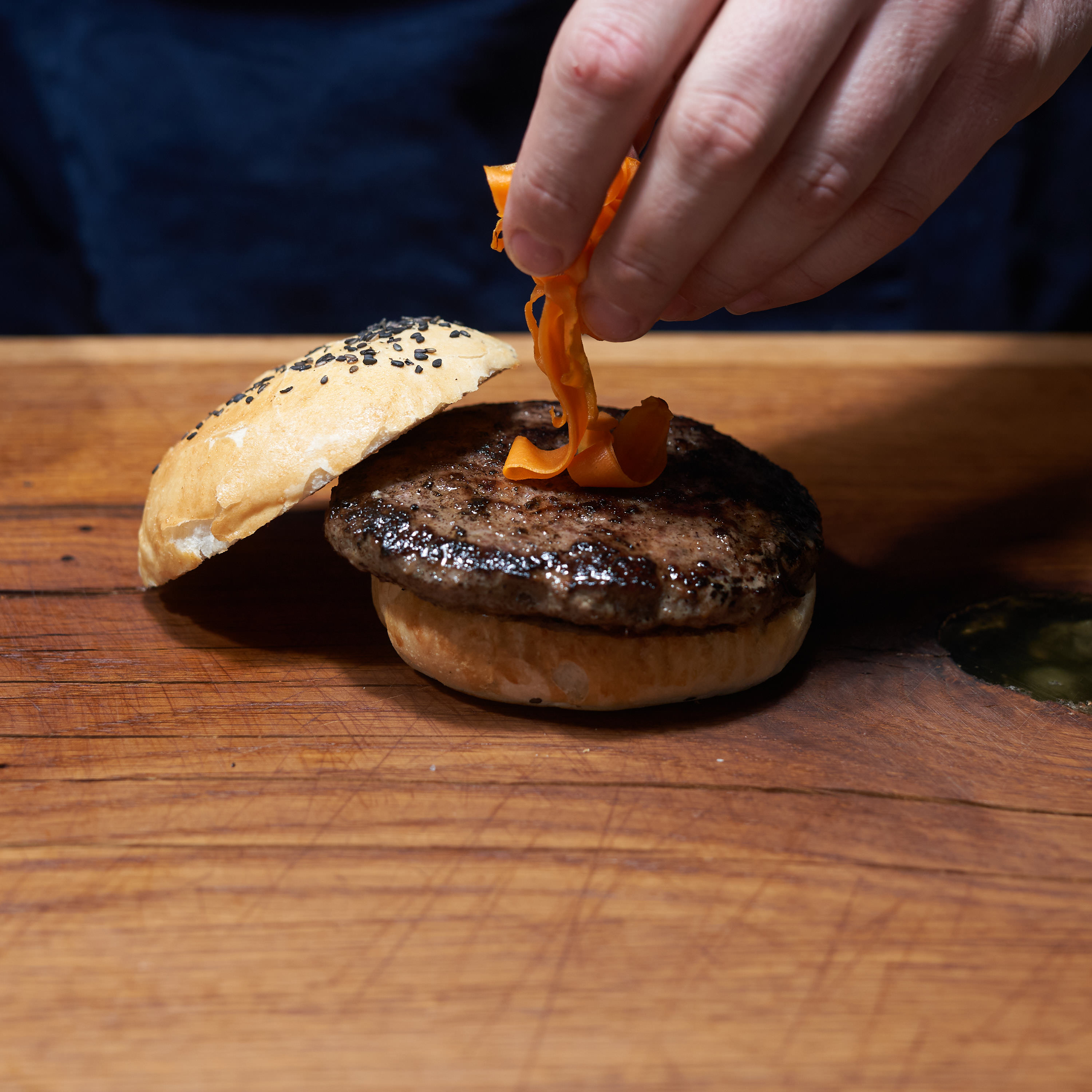 Burger mit Hirsch Patty wird mit Bacon garniert