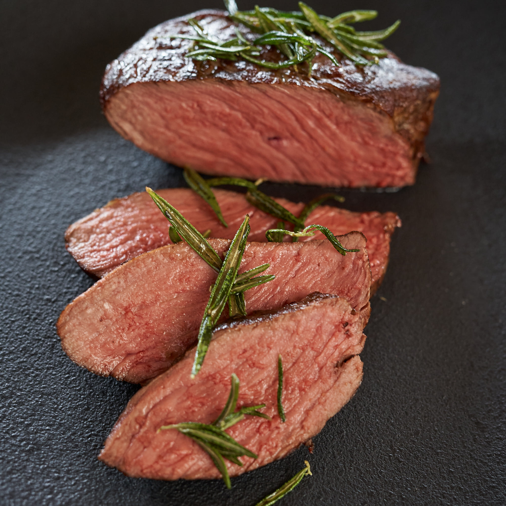 Hueftsteak von der oesterreichischen Kalbin Rosa-gebratenes Huefsteak aufgeschnitten auf Steinplatte