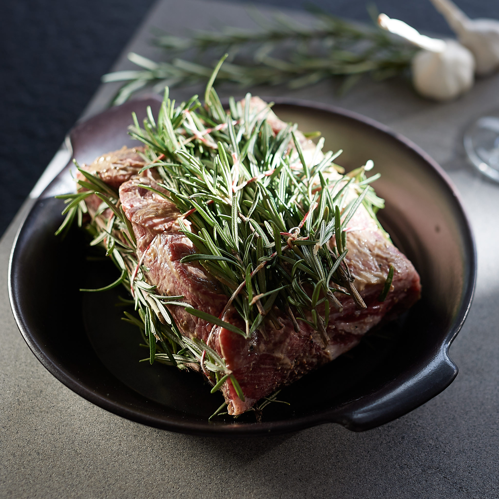 Rumpsteak mariniert mit frischem Rosmarin in schwarzer Schuessel
