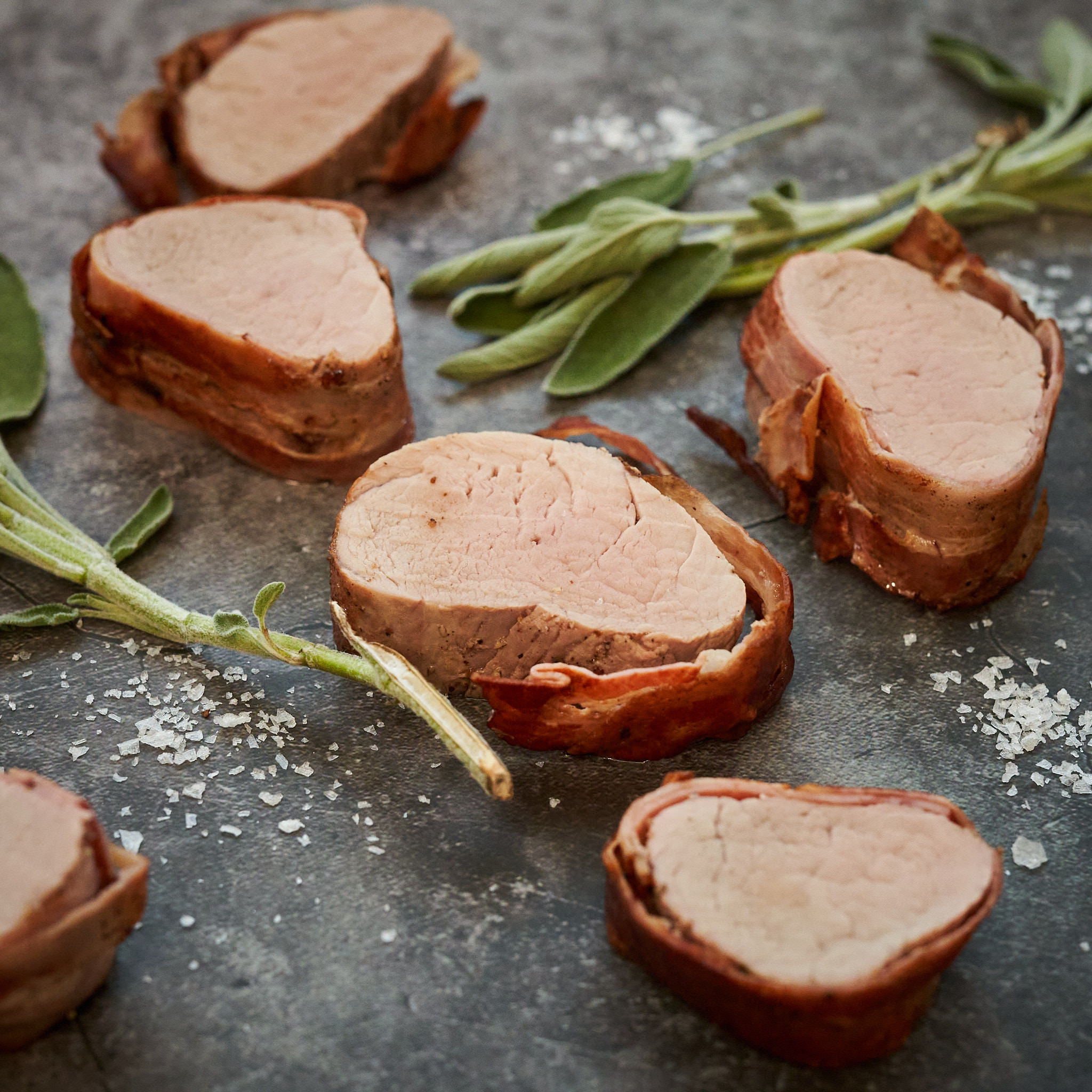 Filet - Schweinslungenbraten vom Strohschwein Gebratene Filetstücke vom Strohschwein auf Marmorplatte mit Salbei-Büdel arrangiert