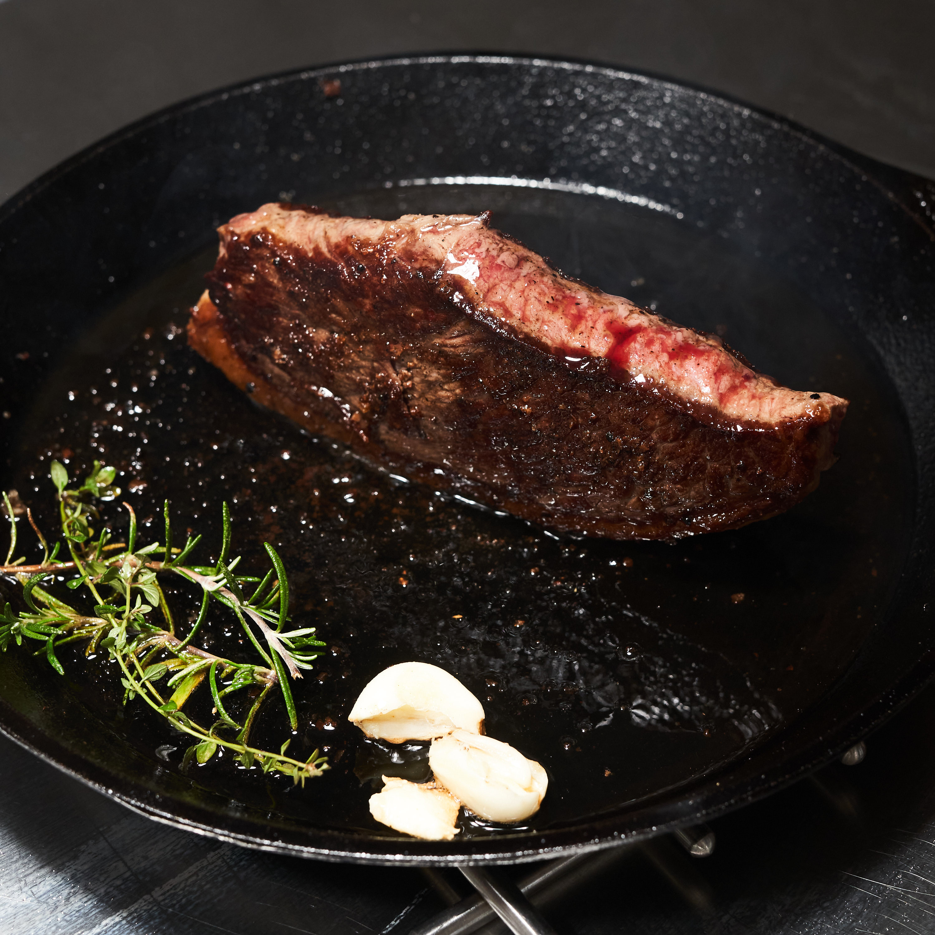 Gegrilltes Picanha Steak in Gusseisenpfanne mit frischem Knoblauch und Rosmarin Gegrilltes Picanha Steak in Gusseisenpfanne mit frischem Knoblauch und Rosmarin