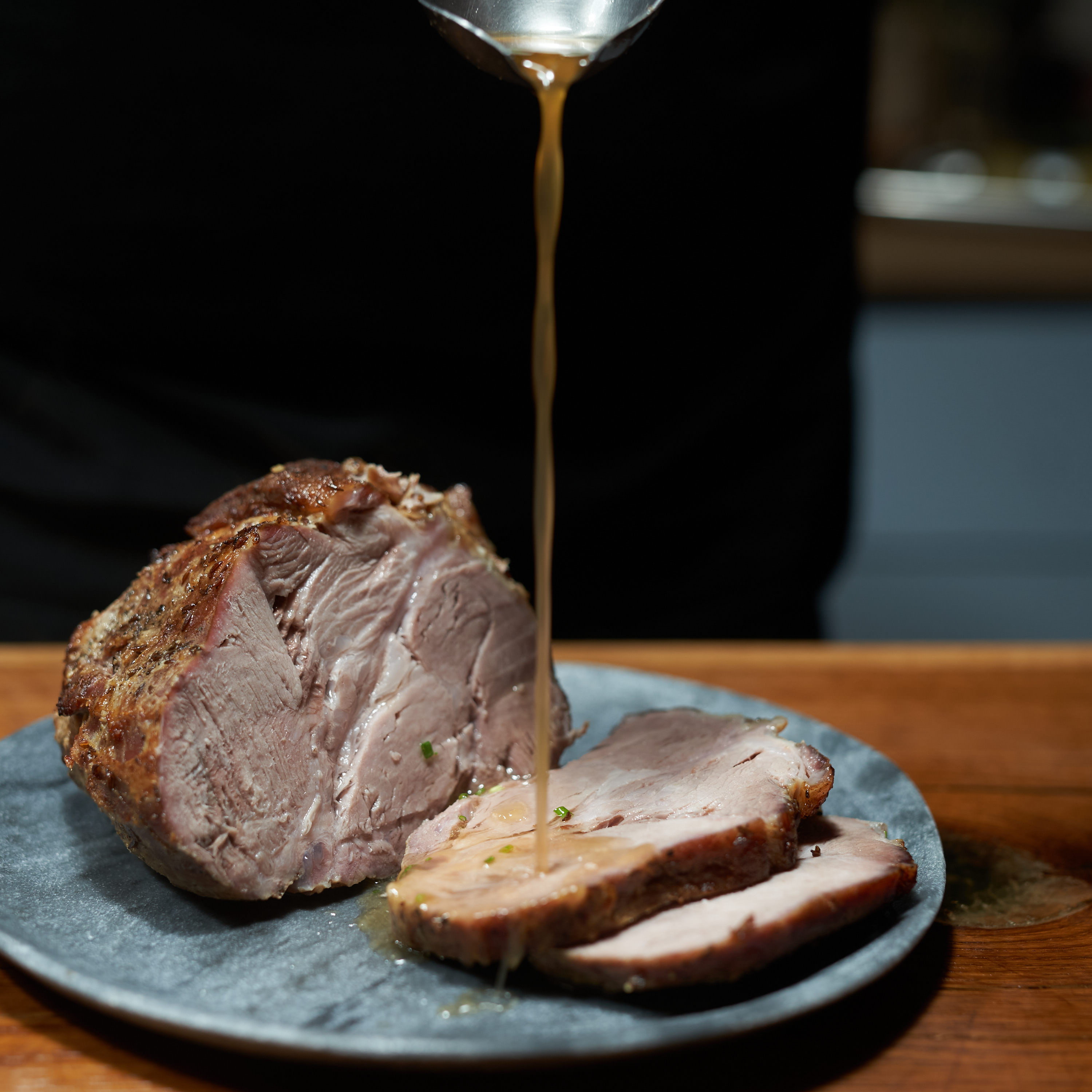 Schweine Schulter vom Strohschwein Bratenstück von der Schweineschulter auf Teller serviert und mit Bratensauce übergossen