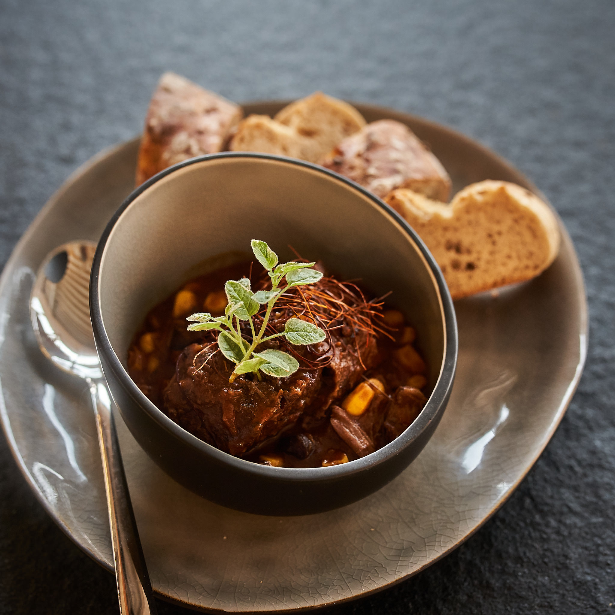 Gulaschfleisch von der hinteren Wade Herzhaftes Gulasch in dunkler Schuessel mit Weissbrot