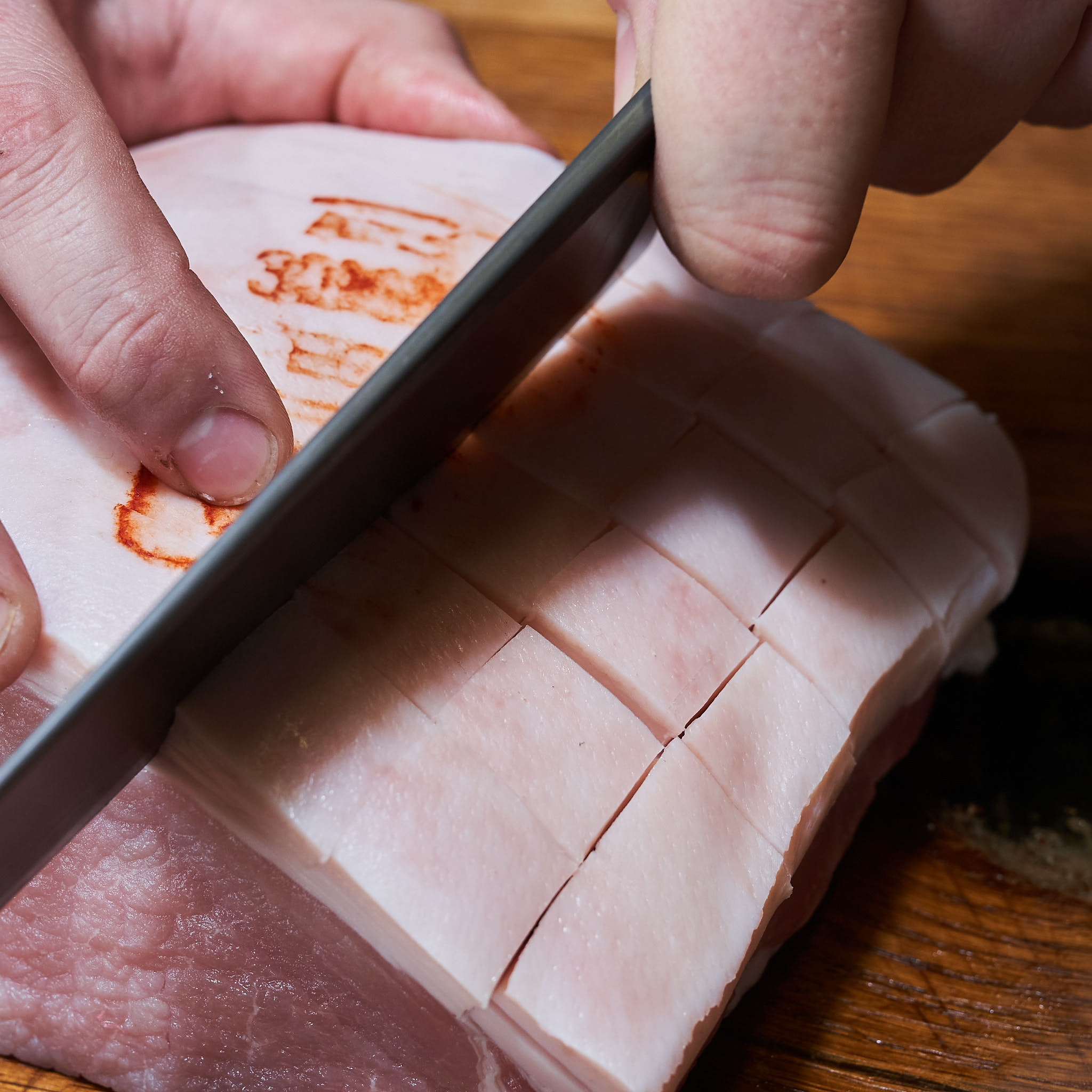 Karree ausgelöst vom Strohschwein Karree Schwarte wird mit Messer eingeschnitten