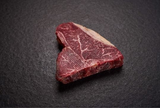 T-Bone Steak auf schwarzer Steinplatte