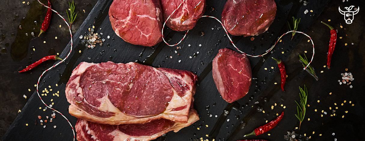 Steak Cuts von Fitmeat auf Steinplatte mit Chilischoten