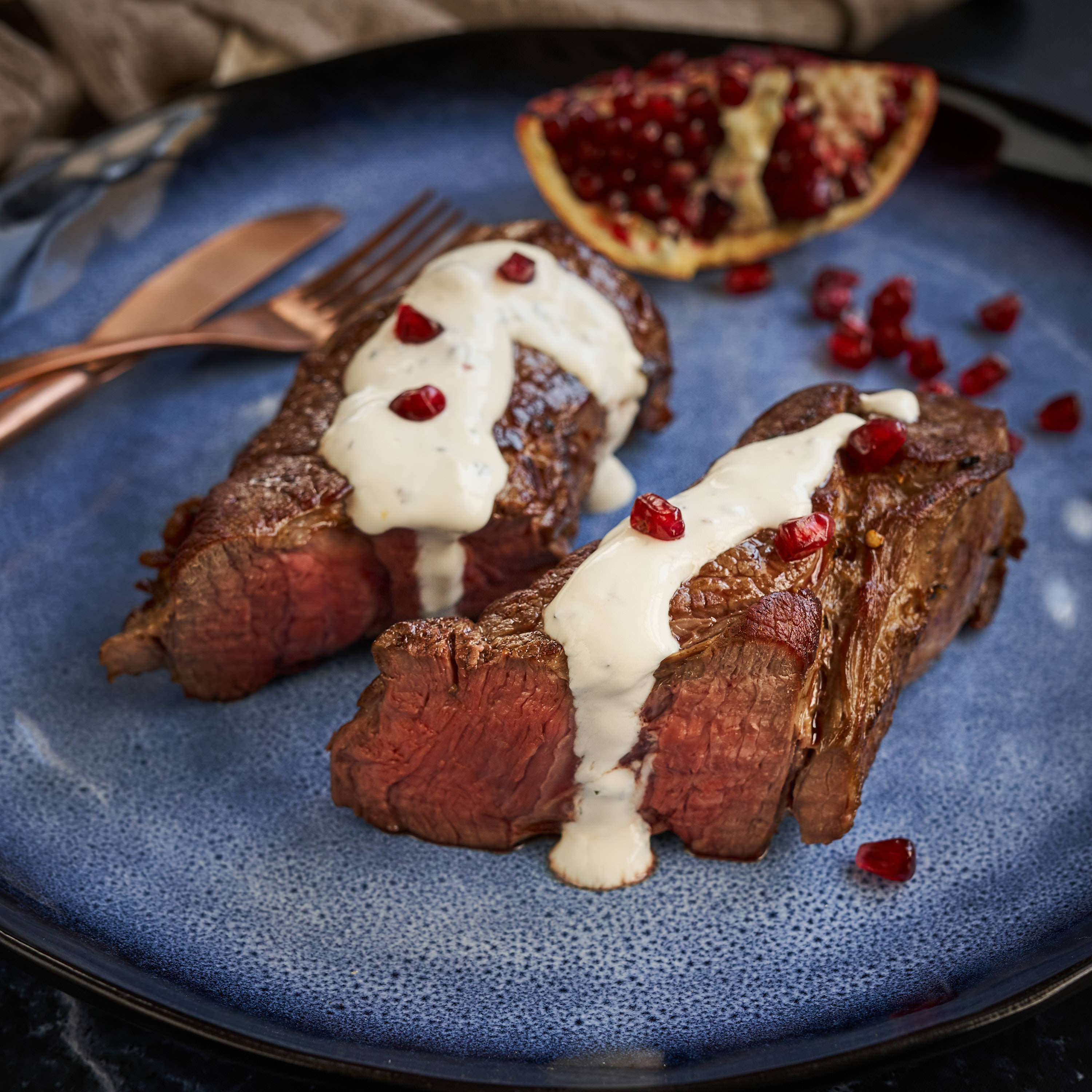 Denver Cut Steaks von der oesterr. Kalbin Saftig gegrillte Denver Cut Steaks auf blauem Teller serviert mit selbstgemachter weisser Sauce