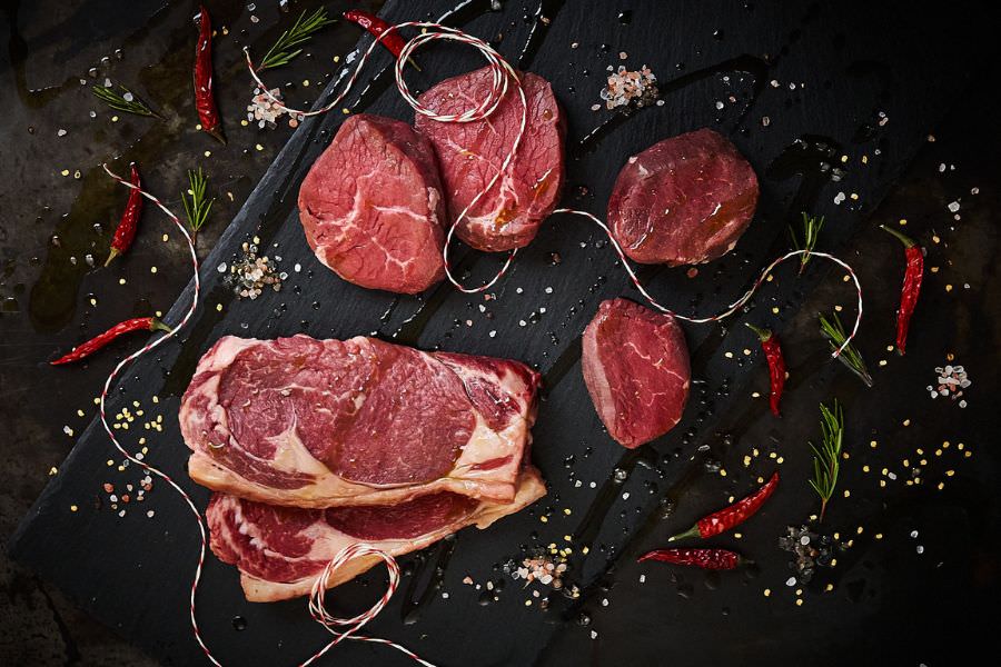 Was gibt’s vom Rind? Cuts zum Grillen, Smoken & Schmoren Auswahl an Steak-Cuts vom Rind auf schwarzem Tablett