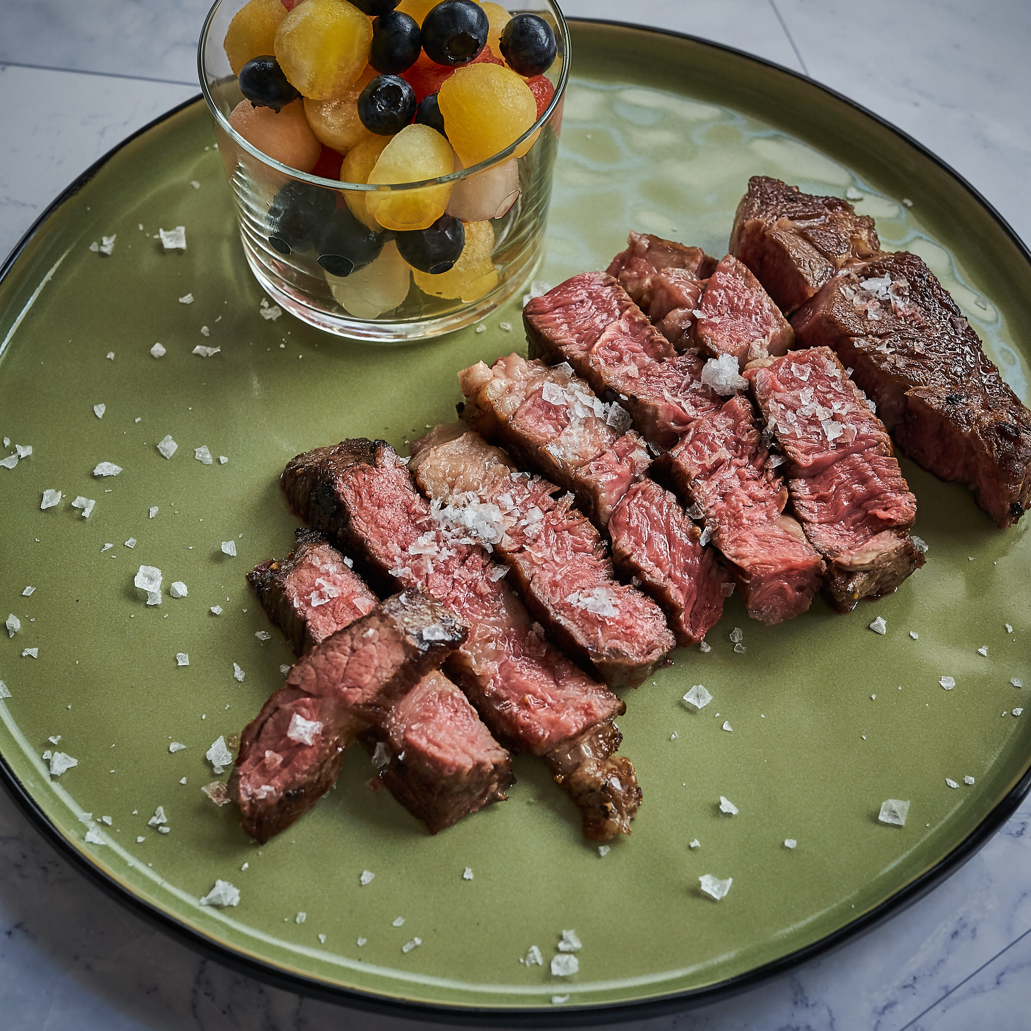 Chuck Steak von der oesterreichischen Kalbin Tranchiertes Chuck Steak auf gruenem Teller mit grobem Meersalz verfeinert