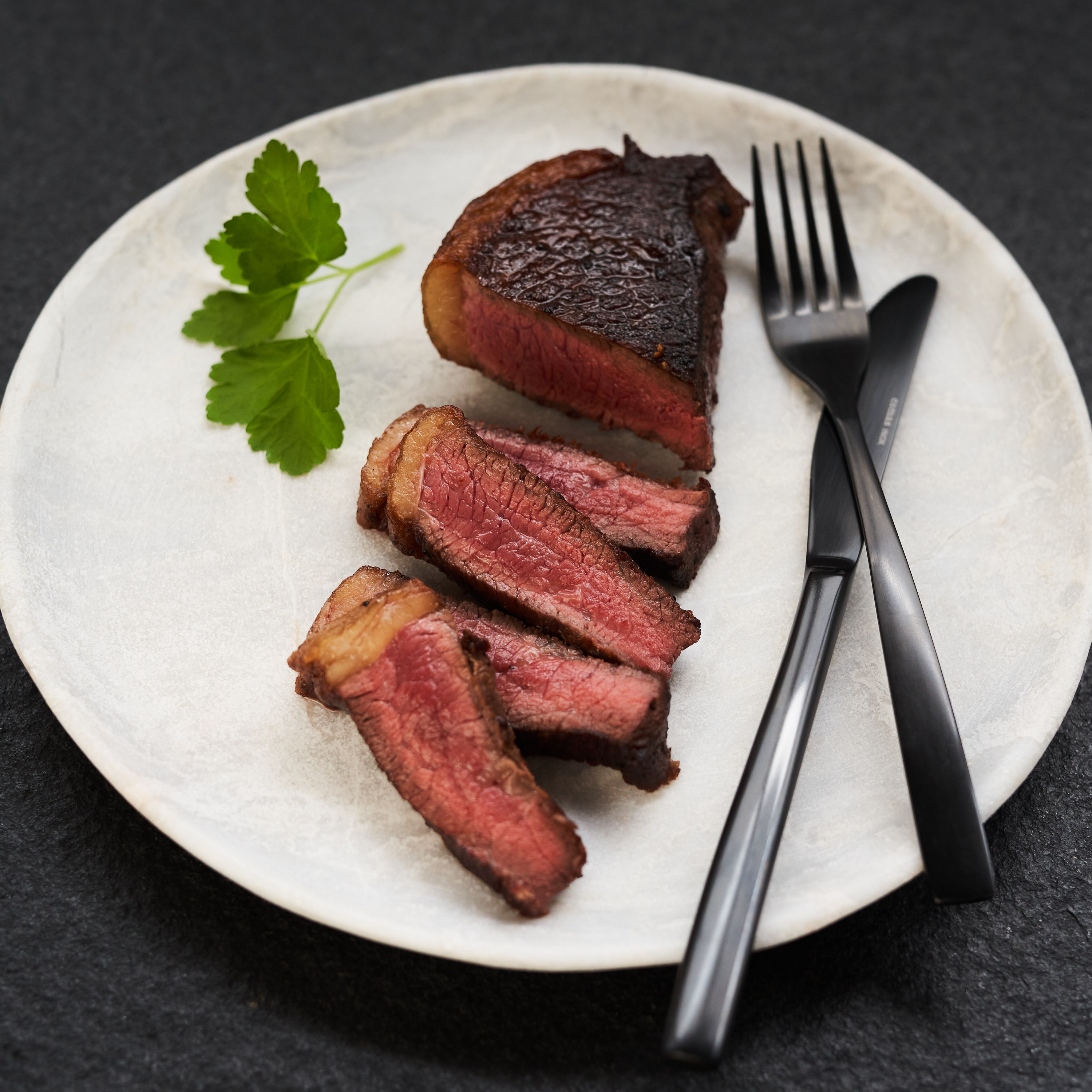 Black Label Picanha Steak gegrillt auf weissem Teller Black Label Picanha Steak gegrillt auf weissem Teller
